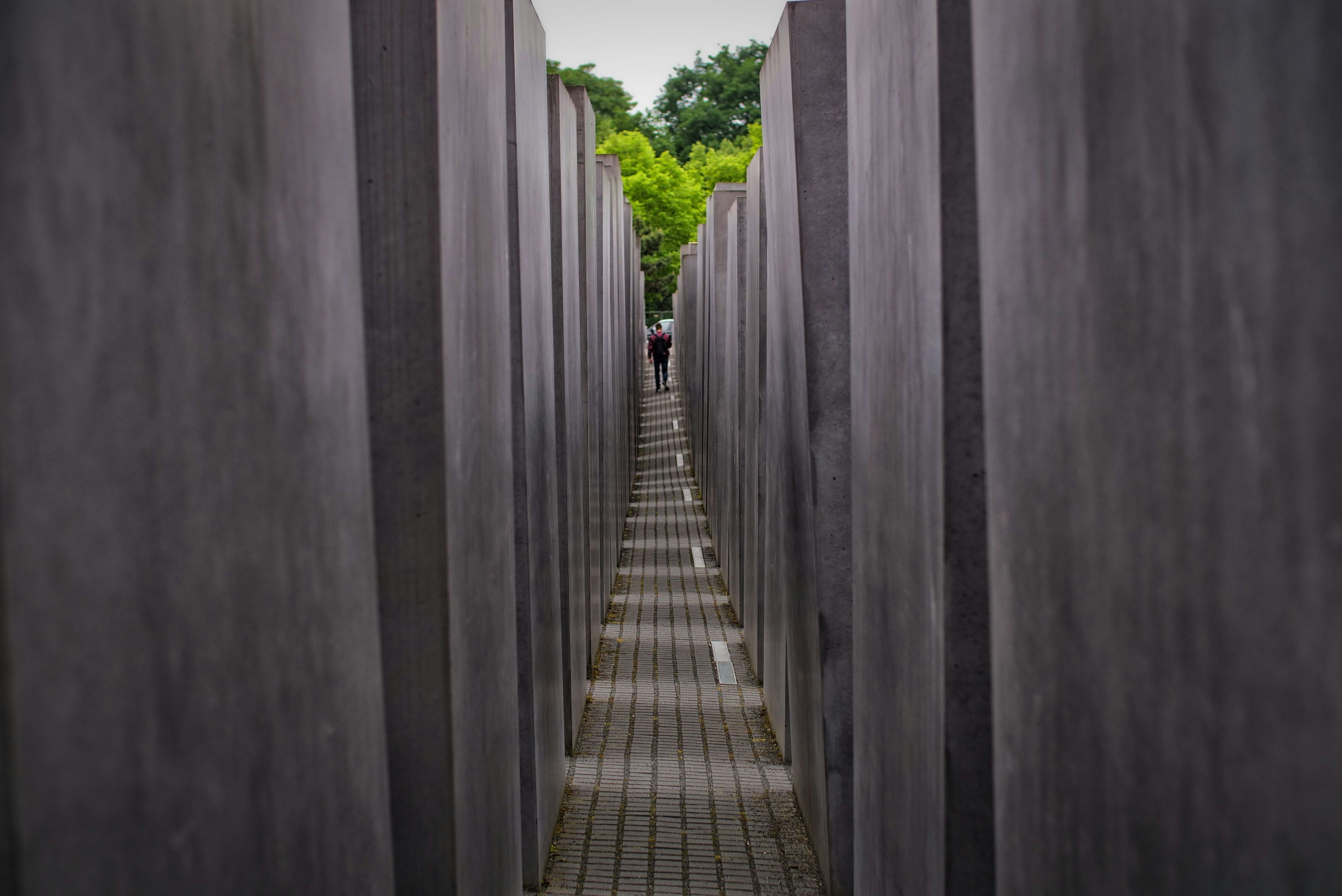 a long row of cement pillars with people walking through them