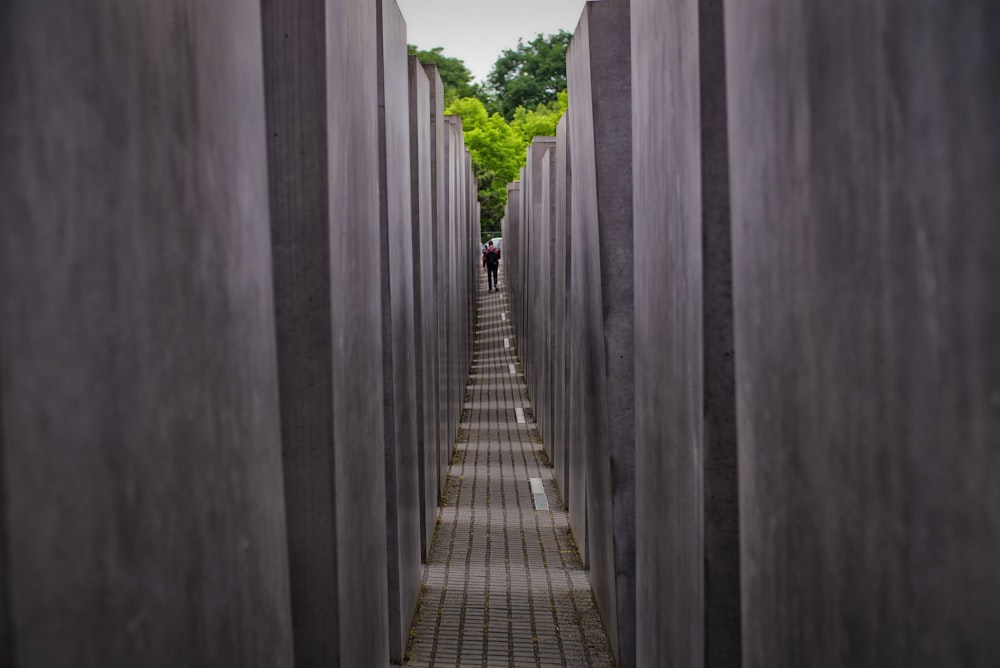 a long row of cement pillars with people walking through them