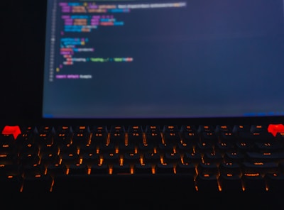 Close-up of hands typing code with vibrant server lights glowing in the background.