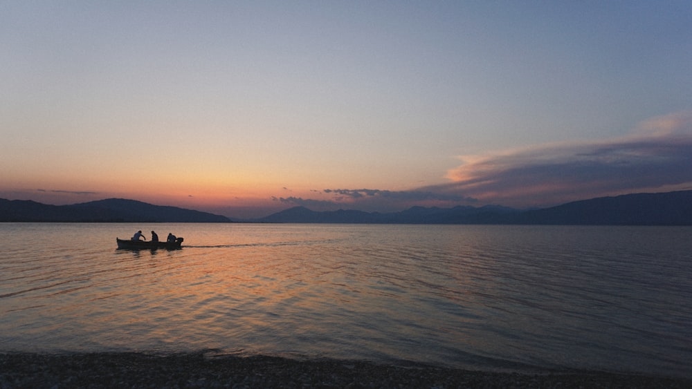 two people in a boat on a lake at sunset