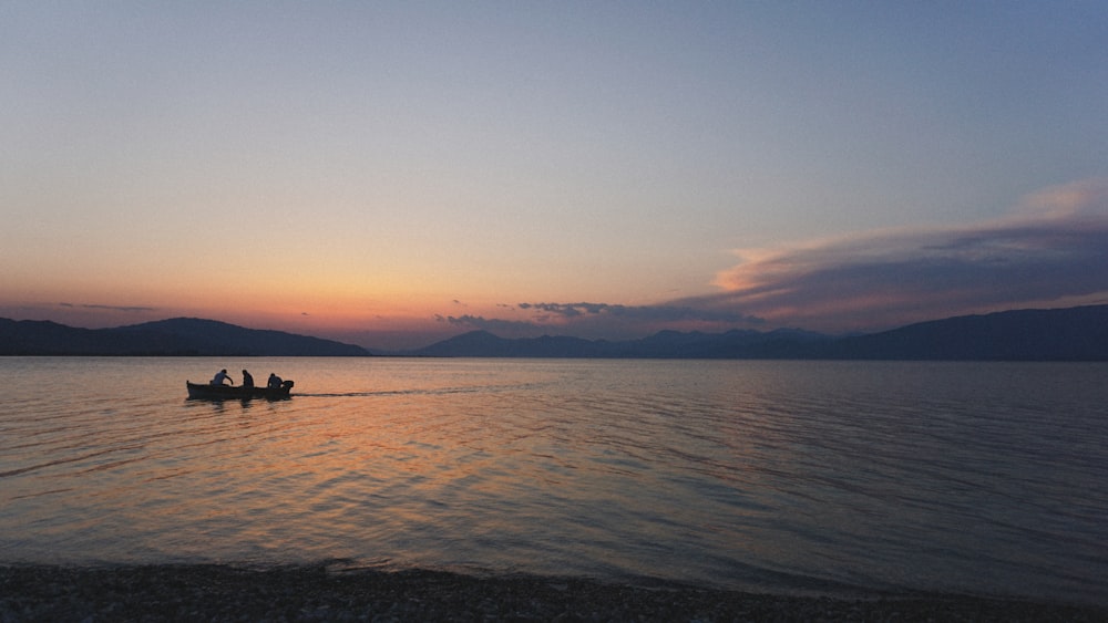 Due persone in una barca su un lago al tramonto