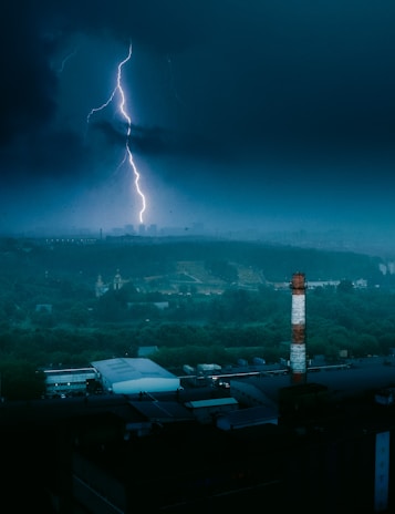 Lightning bolts striking near a tall building equipped with a lightning rod system.