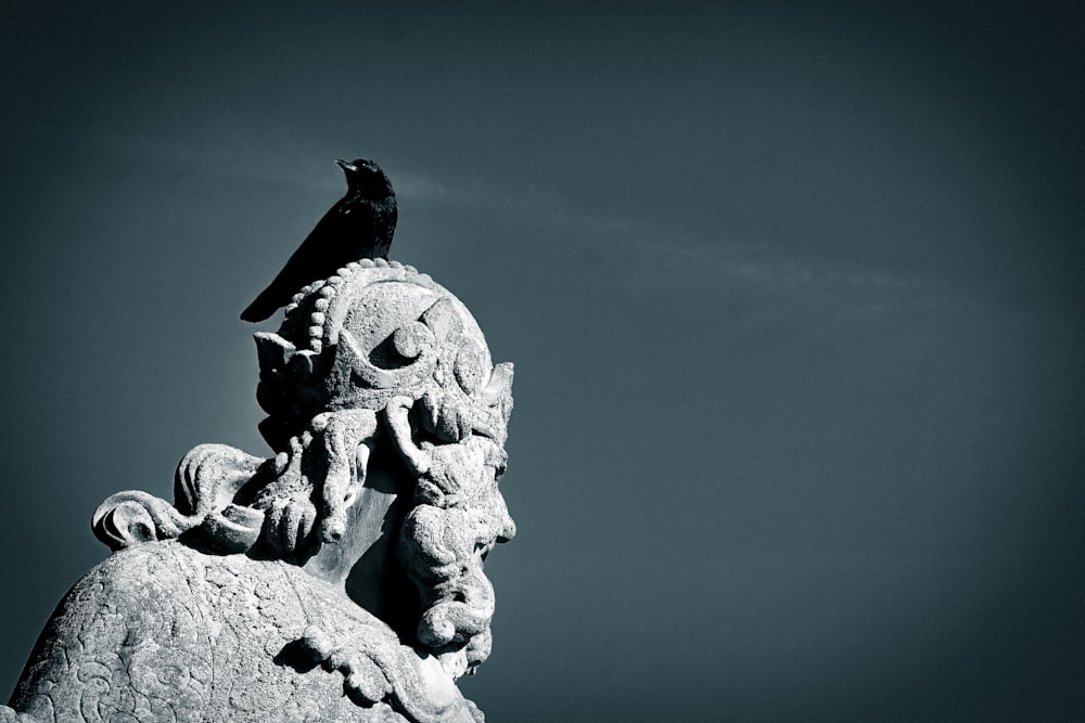 a bird is perched on top of a statue