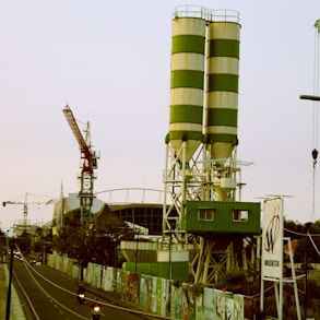 a large green and white tower next to a road