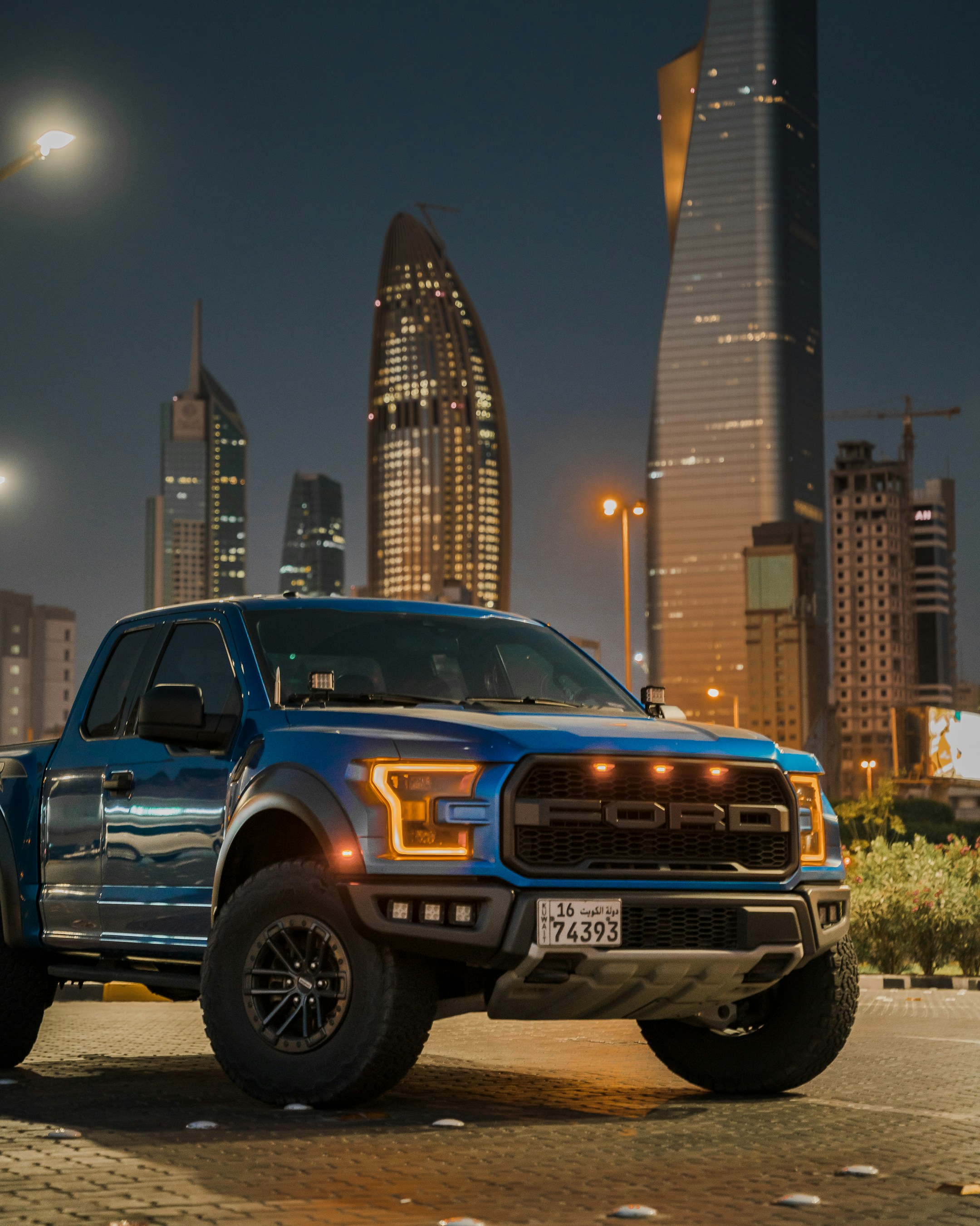 a blue truck parked in front of a city skyline
