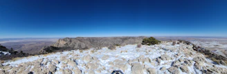 A panoramic view from a rocky summit overlooking rolling mountain ranges.