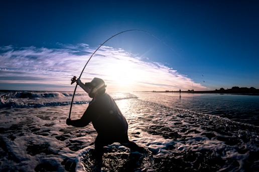 a person standing in the water with a fishing pole