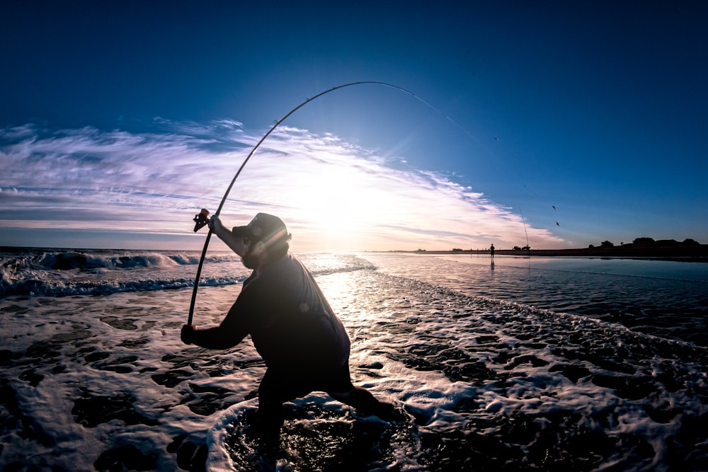 a person standing in the water with a fishing pole