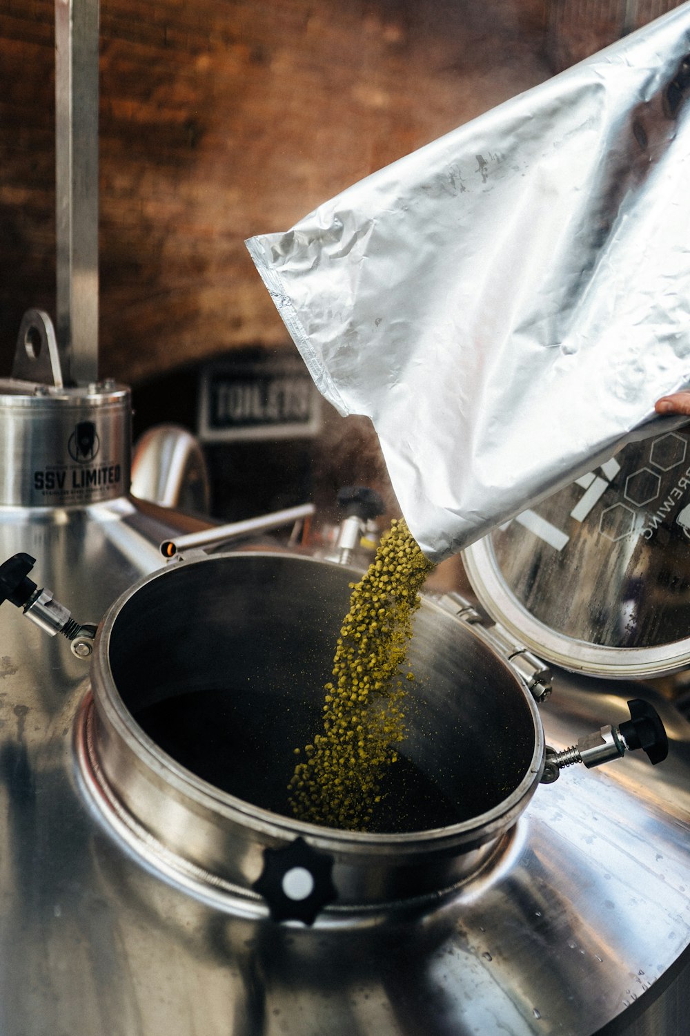 a person pouring mustard into a pot on a stove