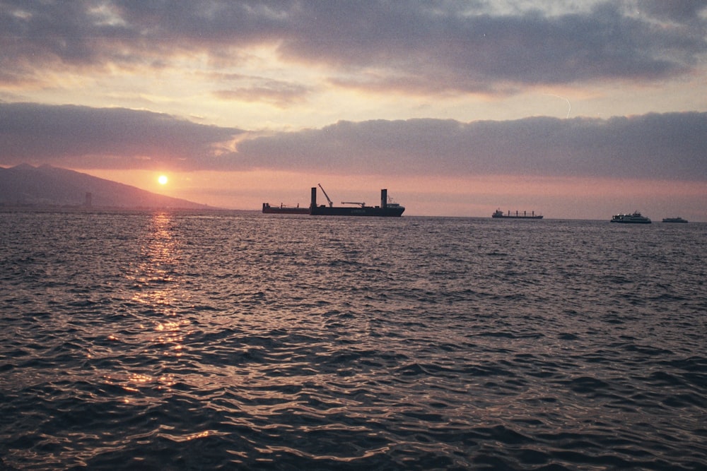 a large cargo ship in the ocean at sunset