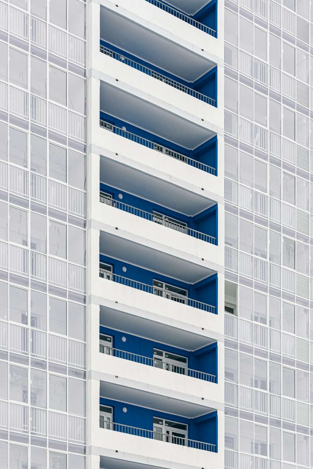 a tall white and blue building with balconies