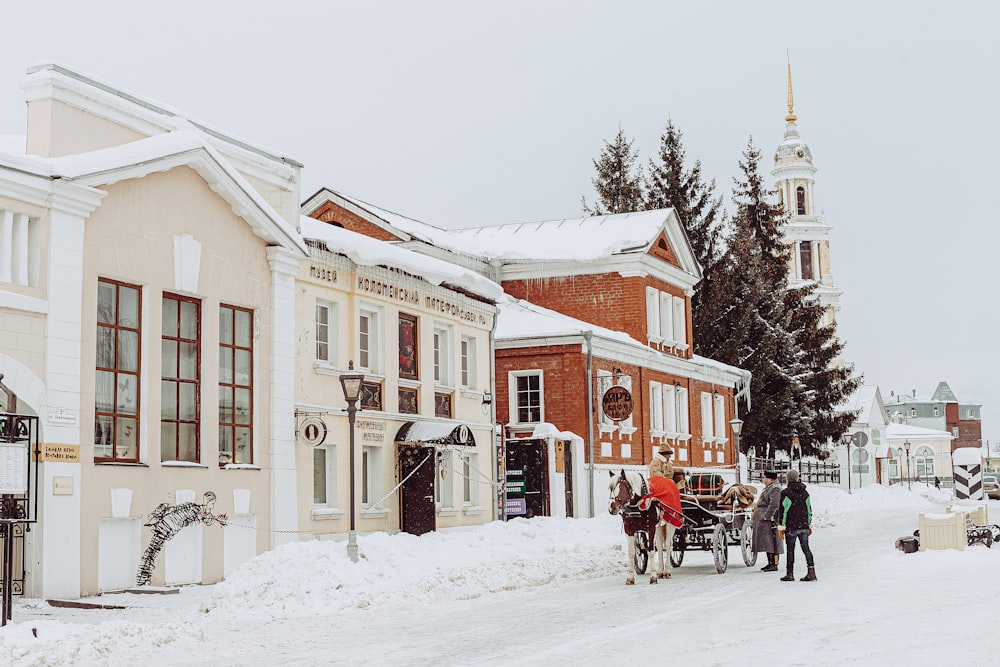 a horse drawn carriage traveling down a snow covered street