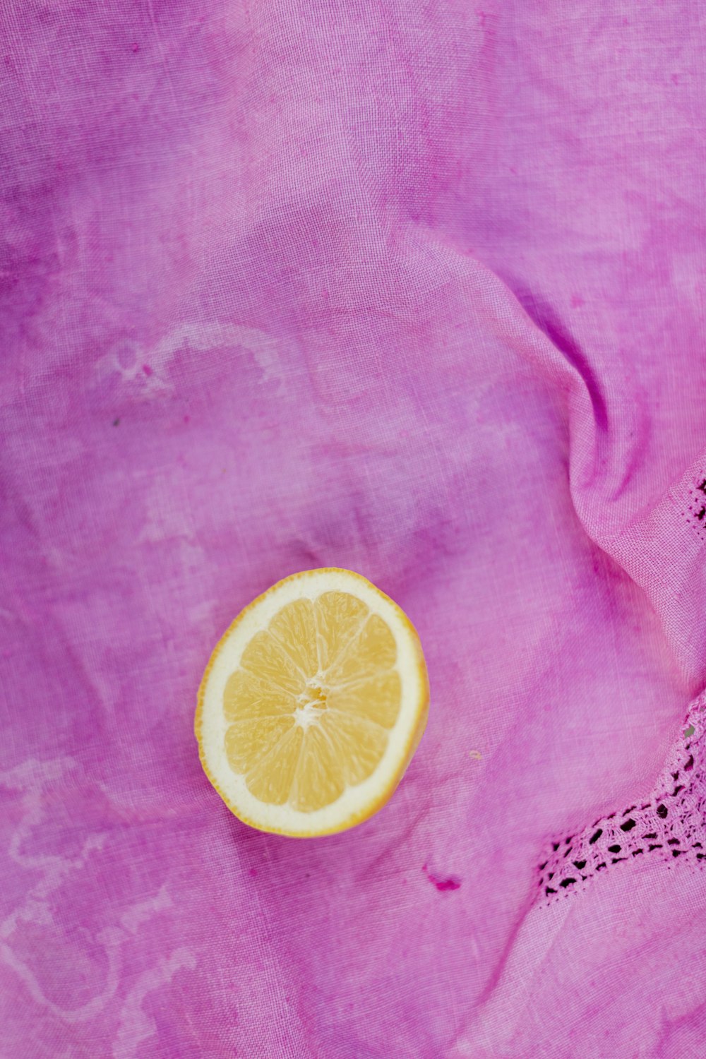 a slice of lemon sitting on top of a pink cloth