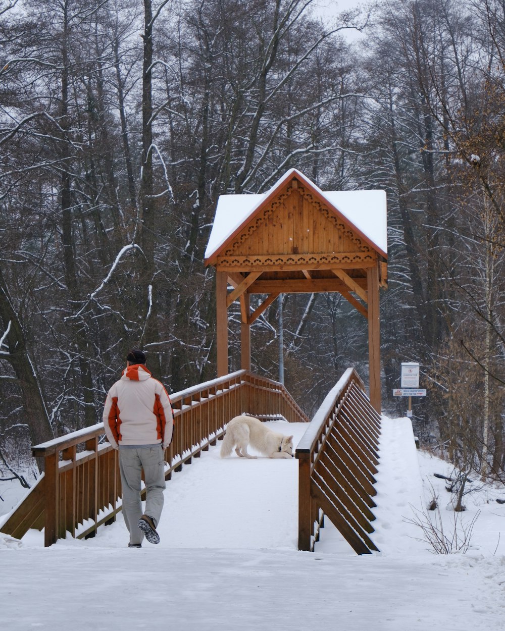 Un hombre caminando por un puente cubierto de nieve