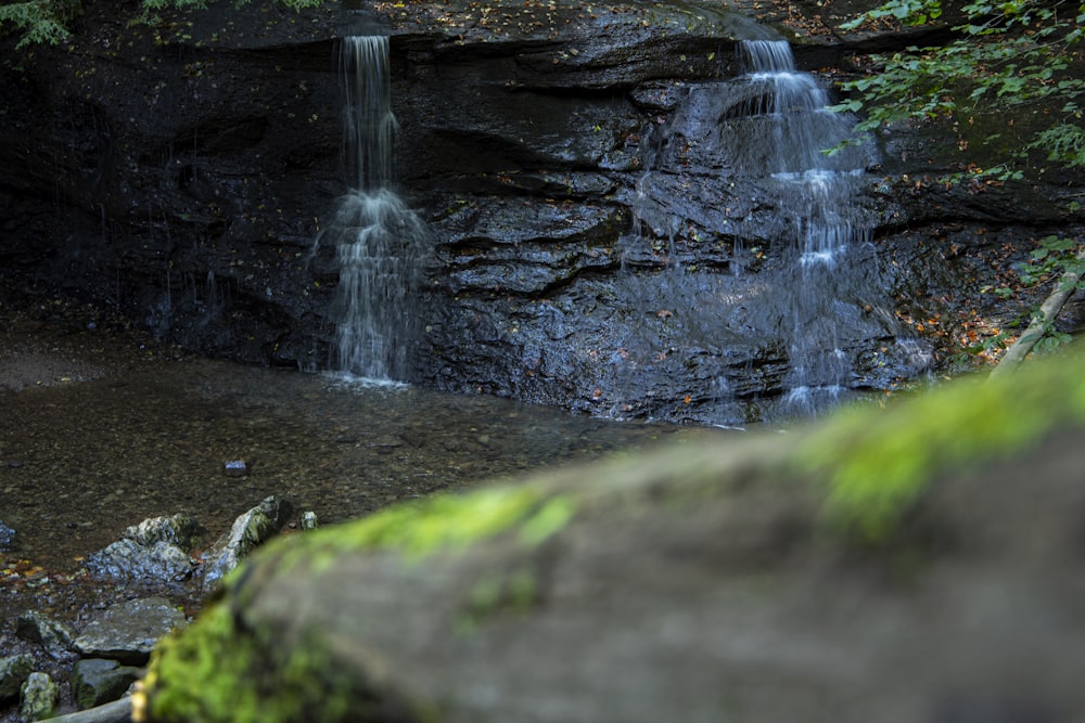 a waterfall in a forest with moss growing on the rocks