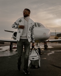 Elevé Group a man holding a bag and standing in front of an airplane