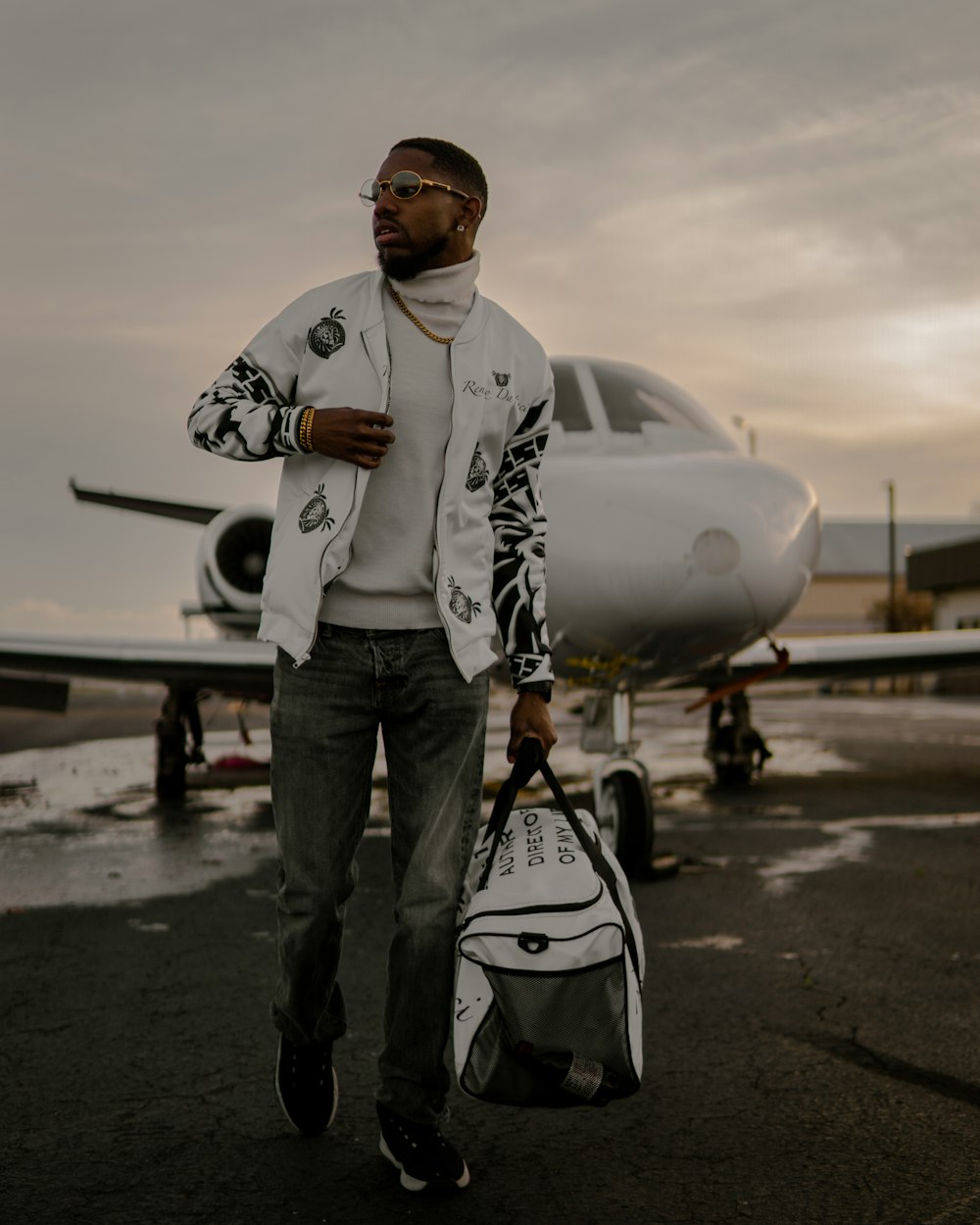 a man holding a bag and standing in front of an airplane