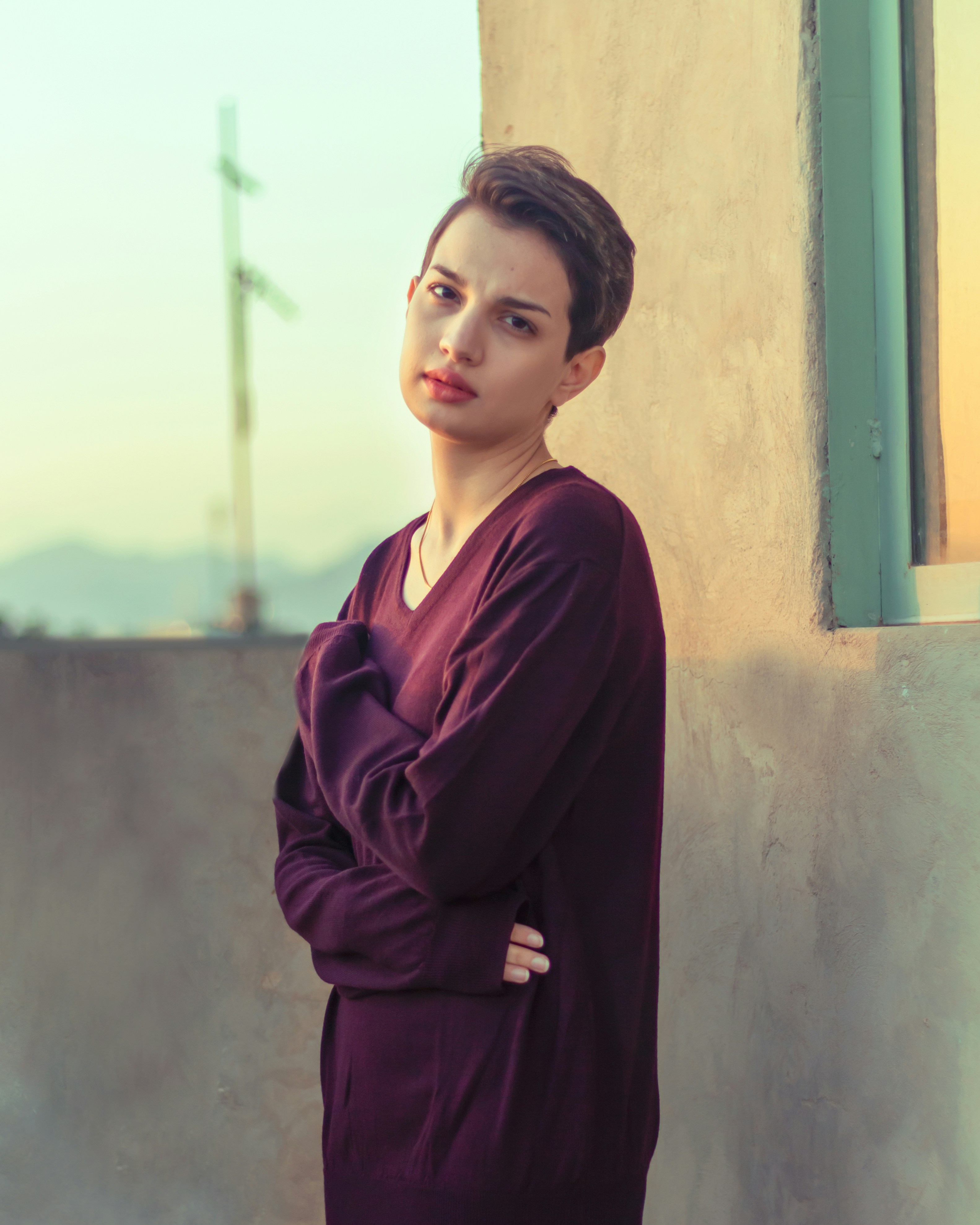 a woman in a purple dress leaning against a wall