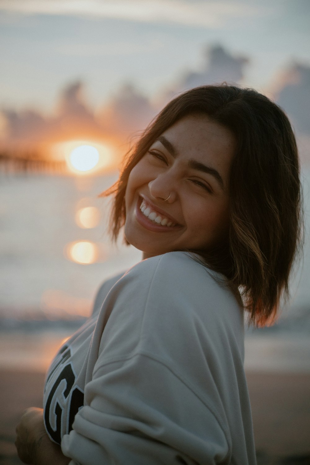 Une femme sourit alors qu’elle se tient sur la plage