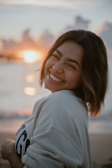 a woman smiles as she stands on the beach