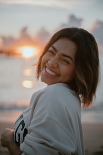 a woman smiles as she stands on the beach