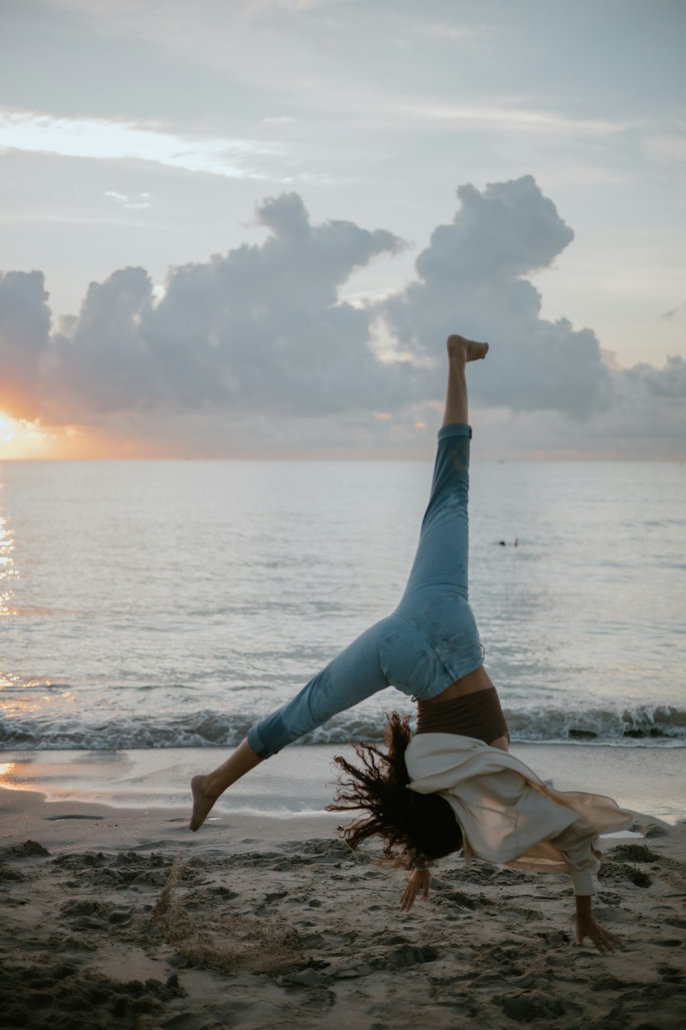 a woman doing a handstand on the beach