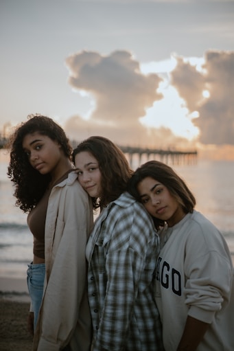 a group of women standing next to each other on a beach