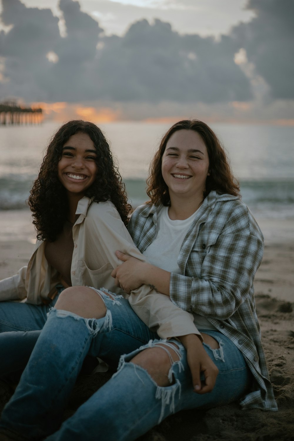 ビーチに座ってカメラに微笑む2人の女性