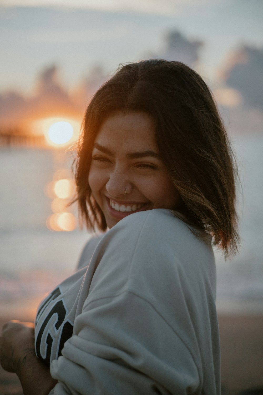 a smiling woman standing on a beach next to the ocean