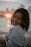 a woman standing on a beach smiling at the camera