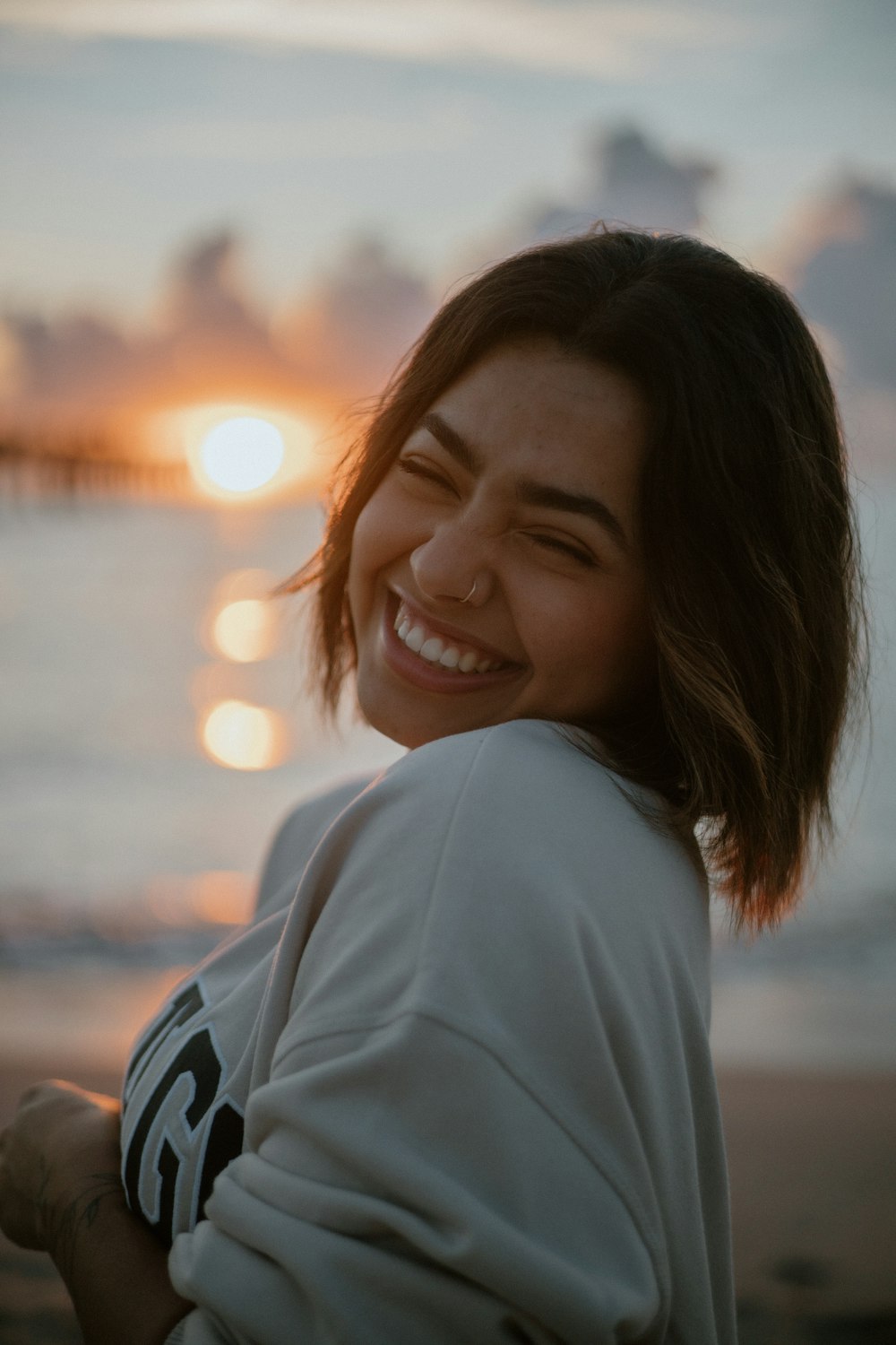 Una mujer parada en una playa sonriendo a la cámara