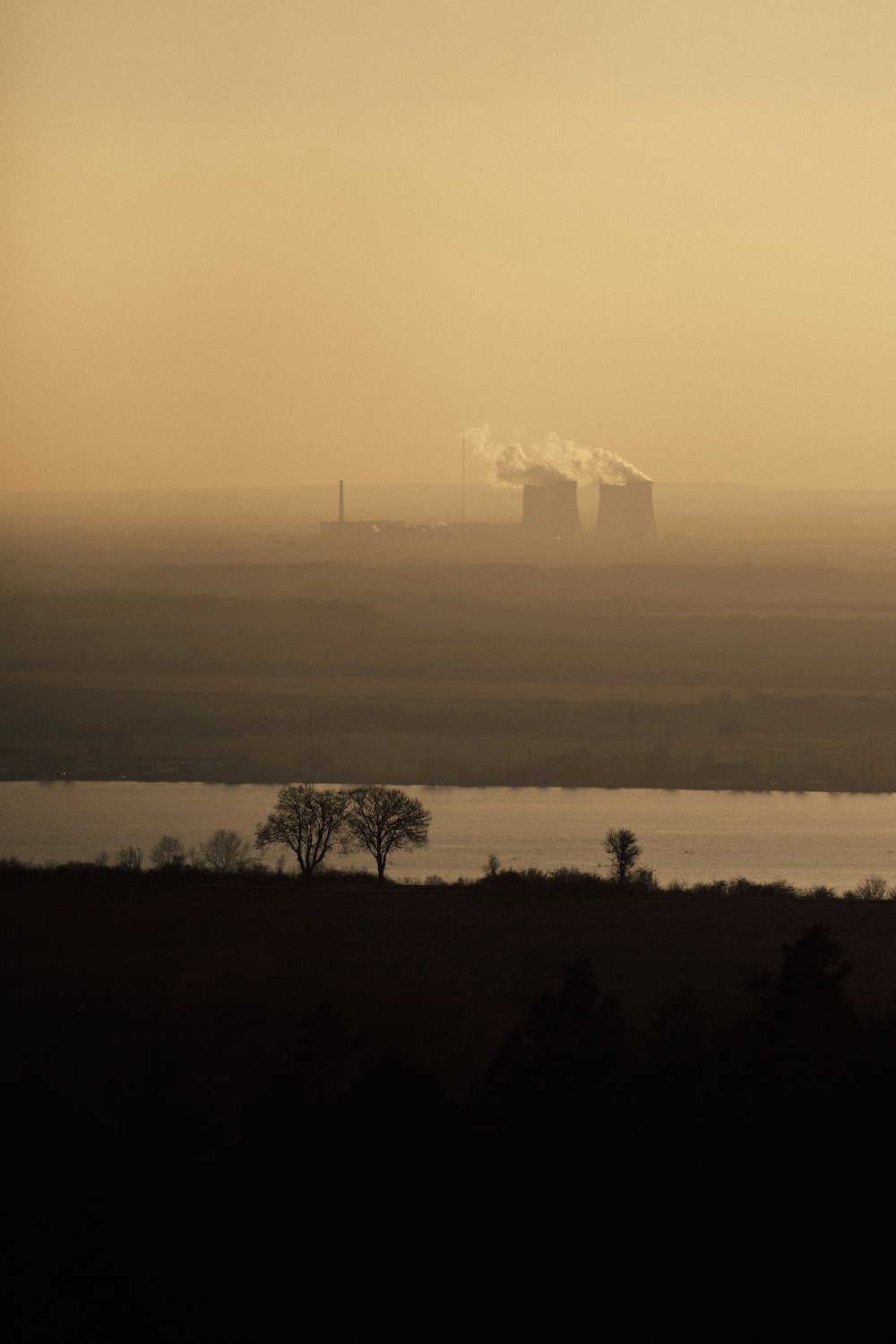 a large body of water with a factory in the distance