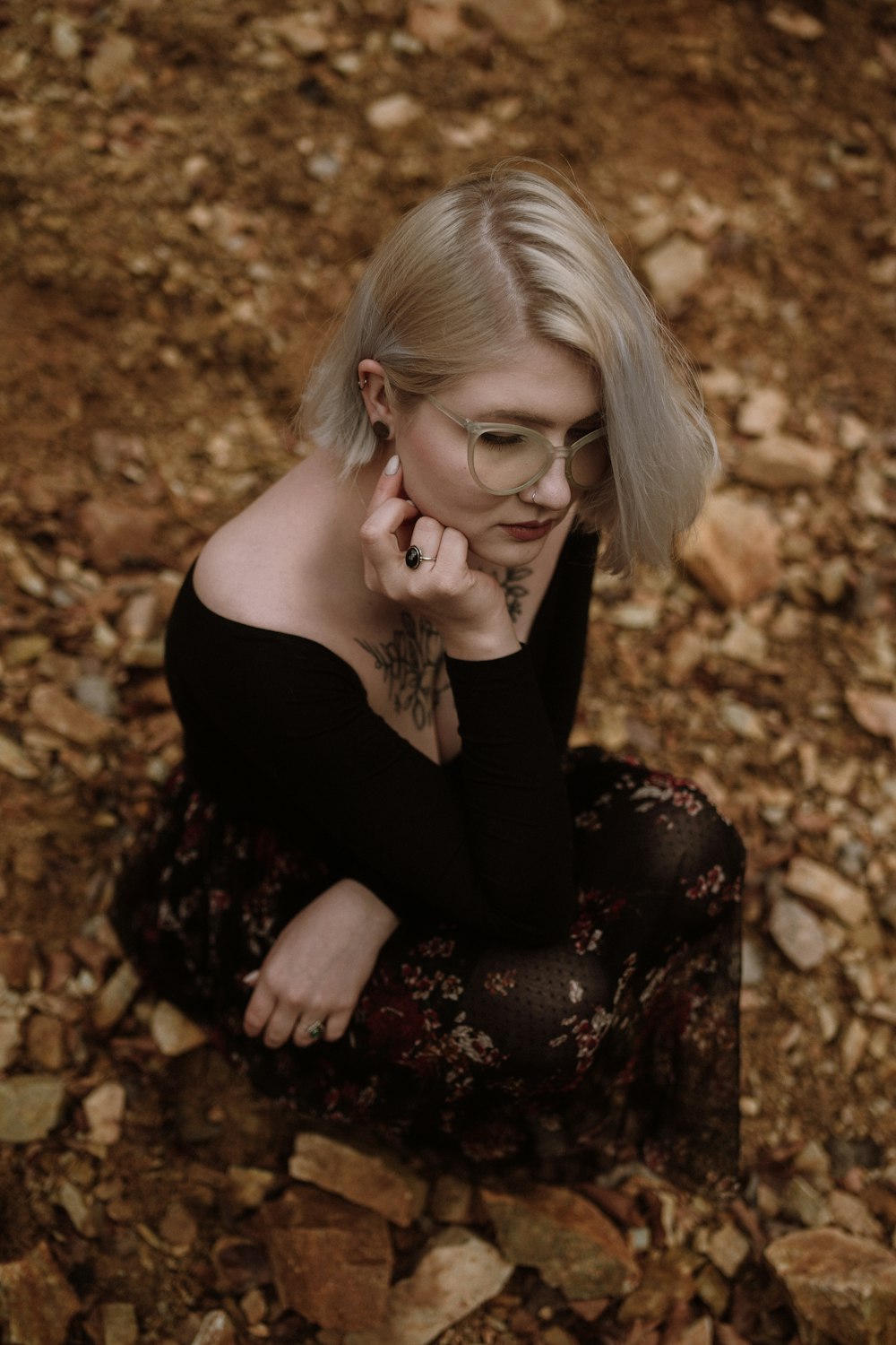 a woman sitting on a rock covered ground