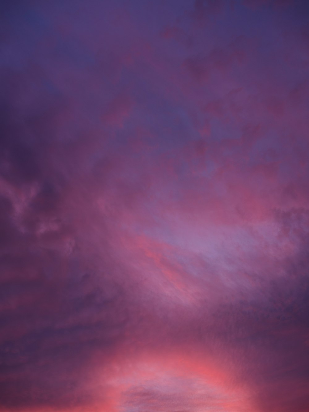 a plane flying in the sky at sunset