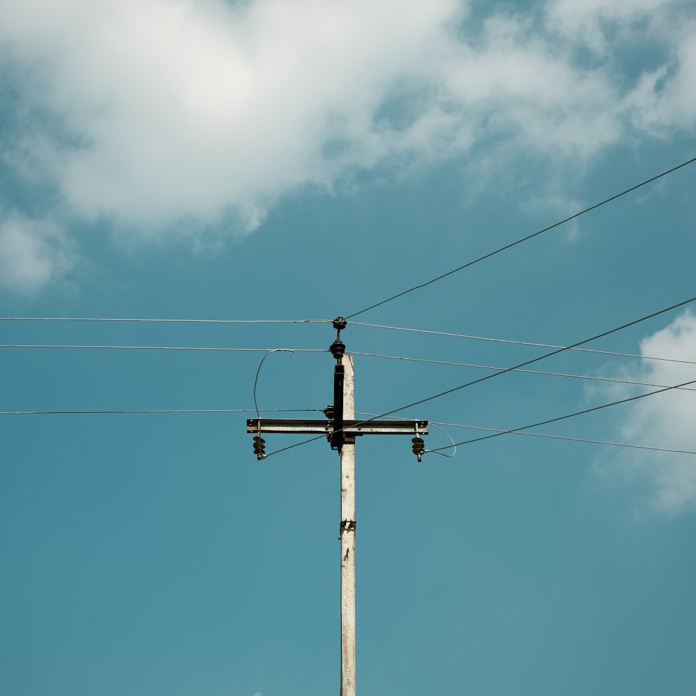 a cross on top of a pole with power lines in the background