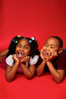 two little girls laying on the ground with their mouths open