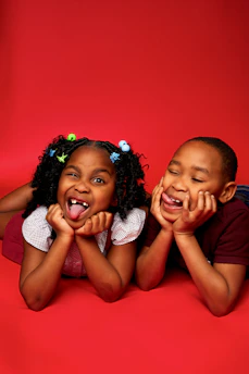 two little girls laying on the ground with their mouths open