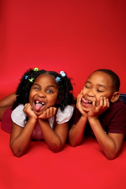 two little girls laying on the ground with their mouths open