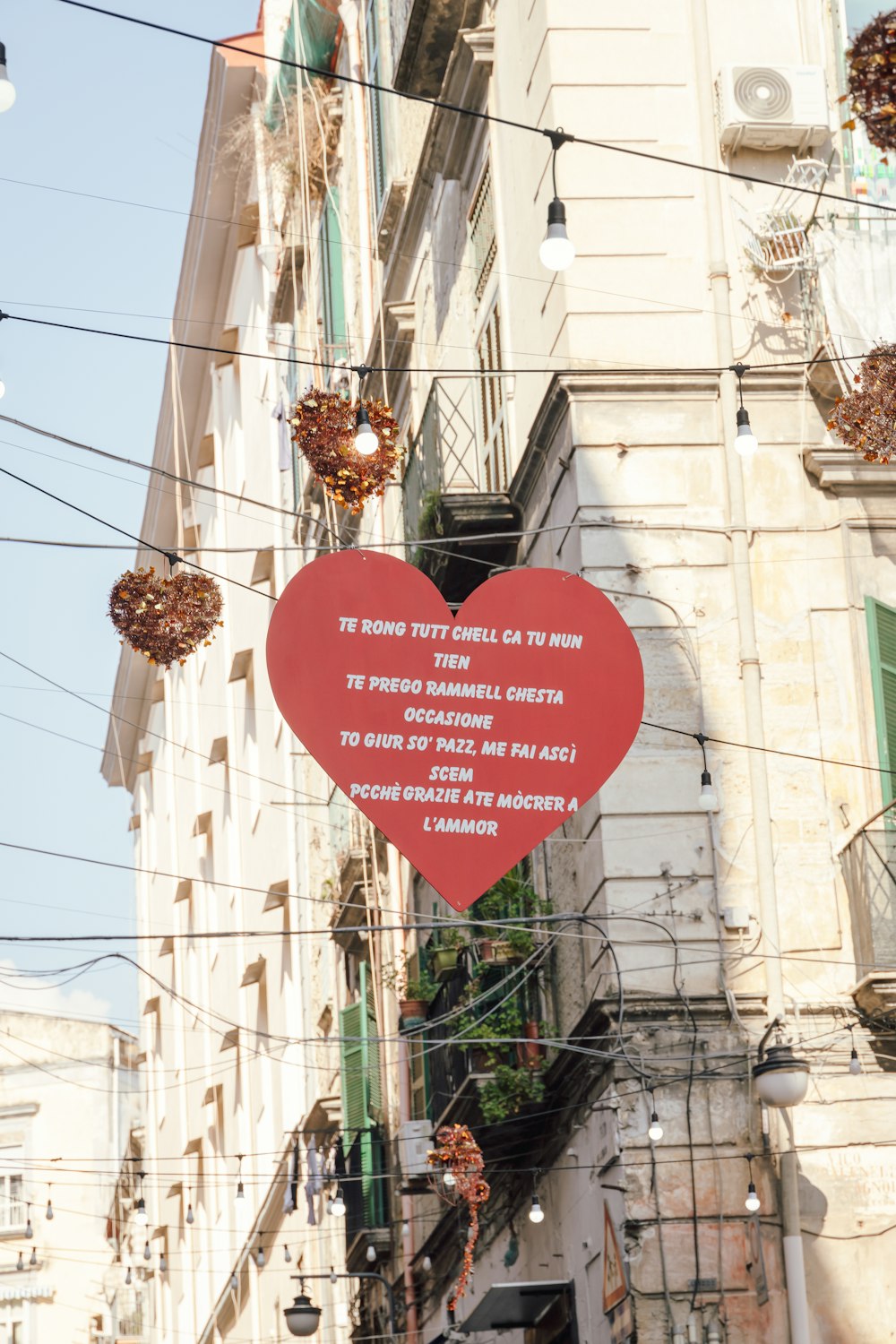 a red heart shaped sign hanging from the side of a building