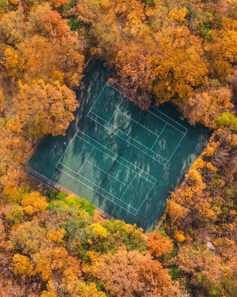 an aerial view of a tennis court surrounded by trees