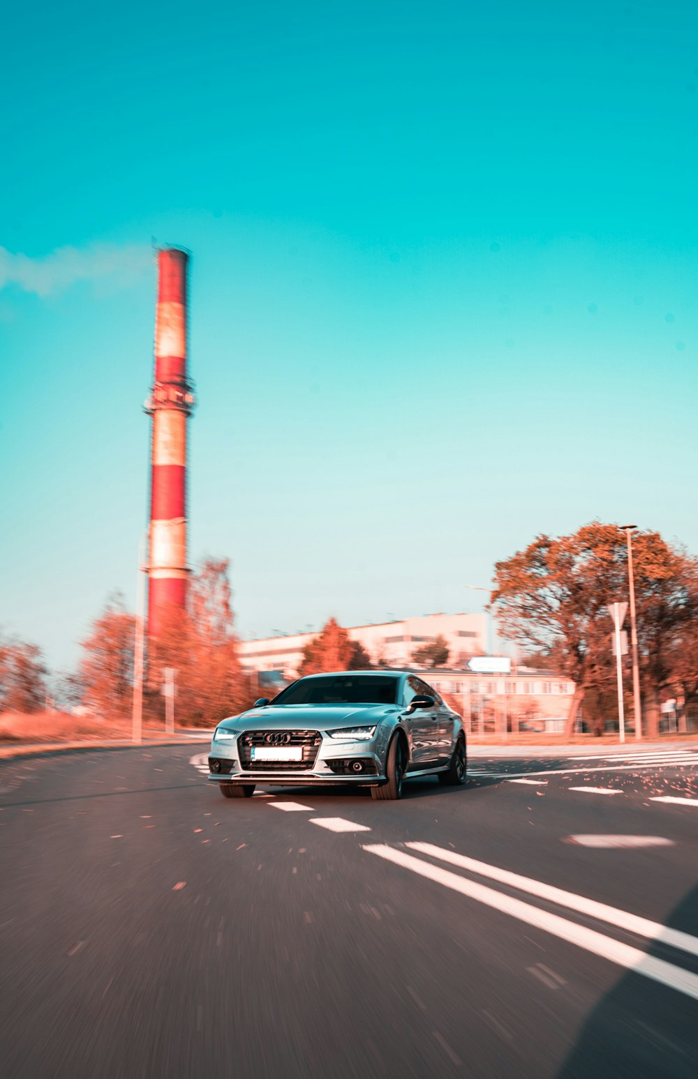 a silver car driving down a street next to a tall tower