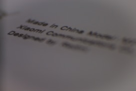 Text printed on a surface, including phrases 'Made in China', 'Xiaomi Communications', and 'Designed by'. The words appear slightly blurred.