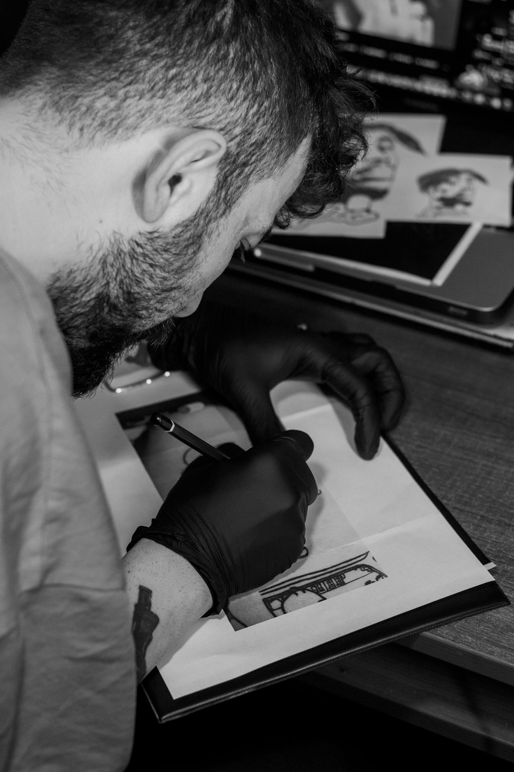 a man with a beard and black gloves working on a piece of paper
