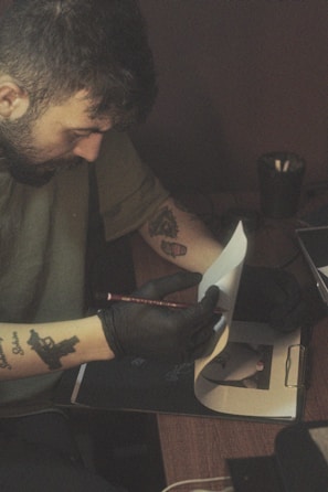 a man with a tattoo on his arm writing on a piece of paper