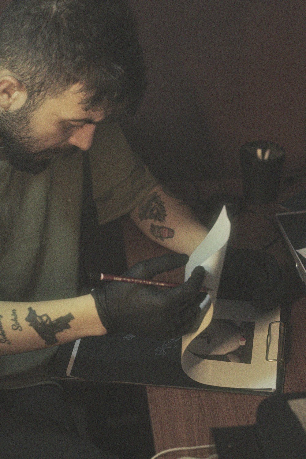 a man with a tattoo on his arm writing on a piece of paper