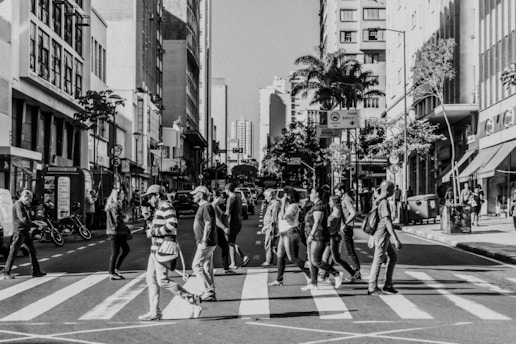 a black and white photo of people crossing the street