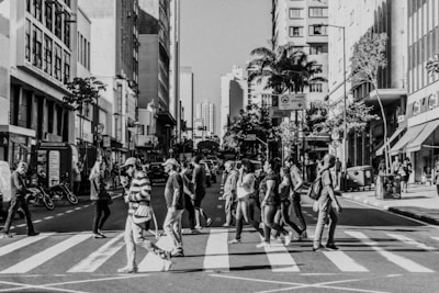 a black and white photo of people crossing the street