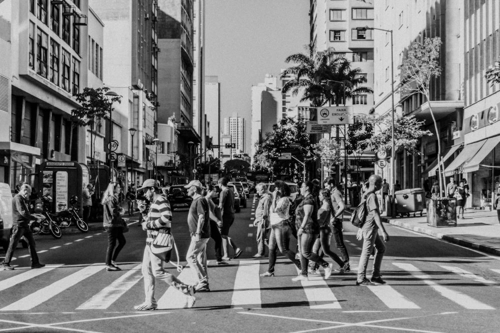 a black and white photo of people crossing the street