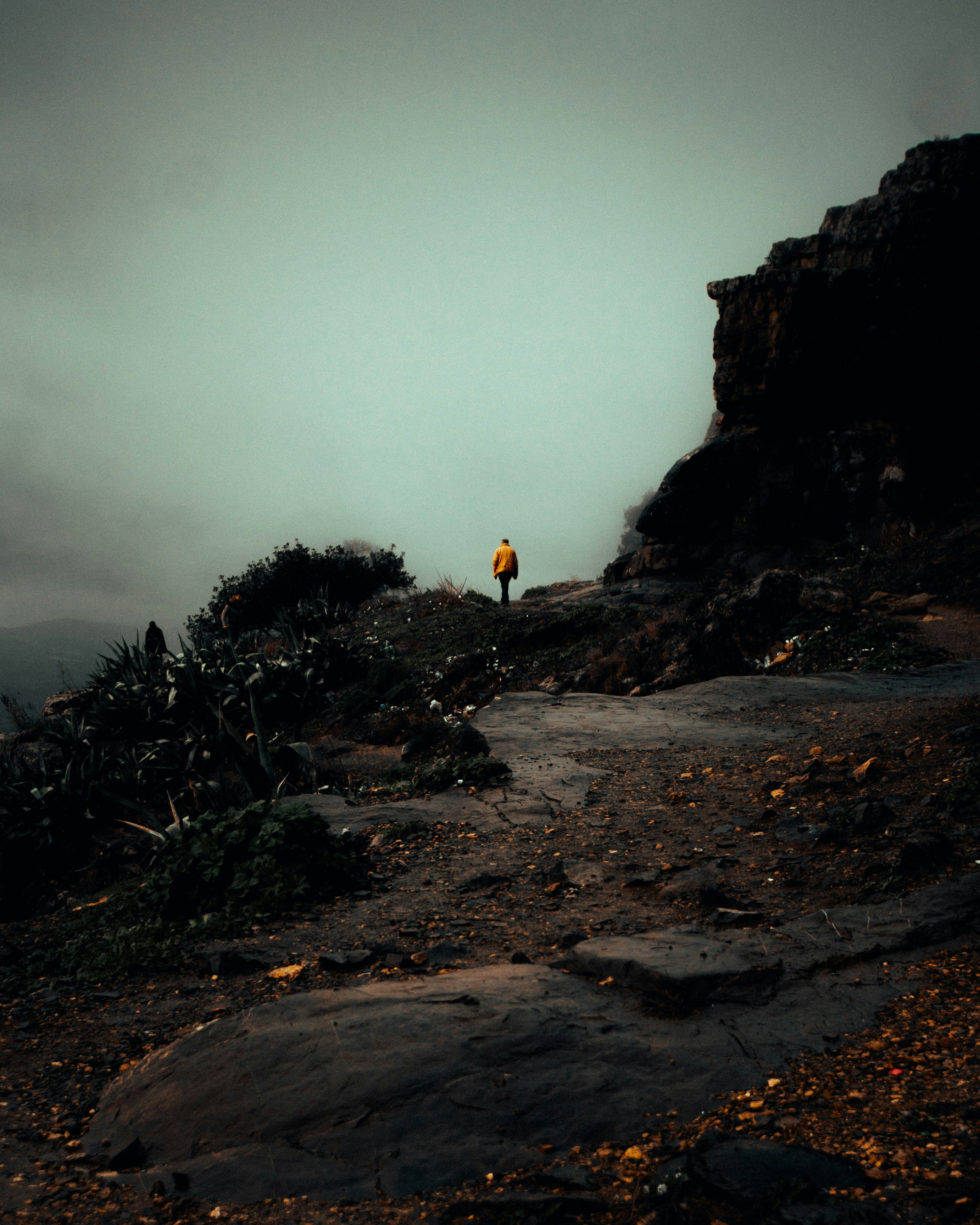 a lone person standing on a rocky trail