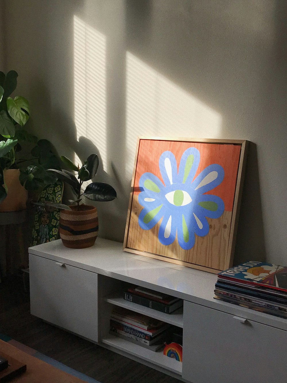 a picture of a flower on a shelf in a room